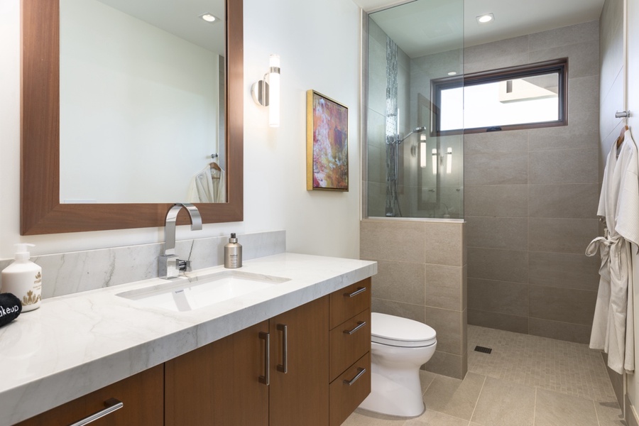 Ensuite guest bathroom with a walk-in shower, custom storage and natural lighting.