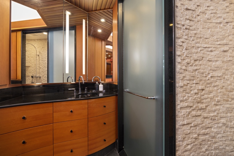 Step into your sleek bathroom featuring rich wood vanity, modern fixtures, and elegant stone textures creating a spa-like sanctuary for your stay.