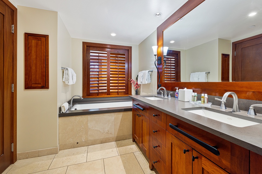 Unwind in your elegant bathroom featuring dual vanities, a soaking tub, and rich wood accents. Plush towels and thoughtful amenities ensure your comfort during your stay.