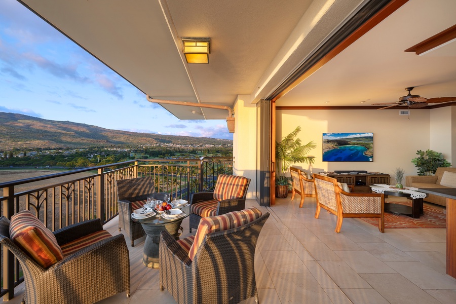 Inviting lanai space with comfortable seating and a dining set, offering a panoramic view of rolling hills under a soft sunset sky.