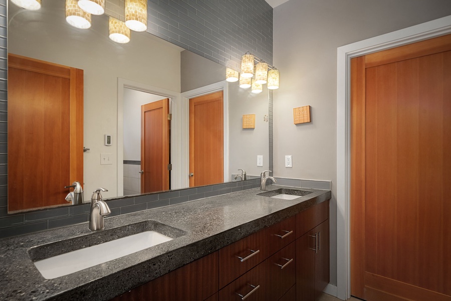 Start your mornings in this sleek double vanity bathroom with modern fixtures and warm wood accents for a spa-like experience.