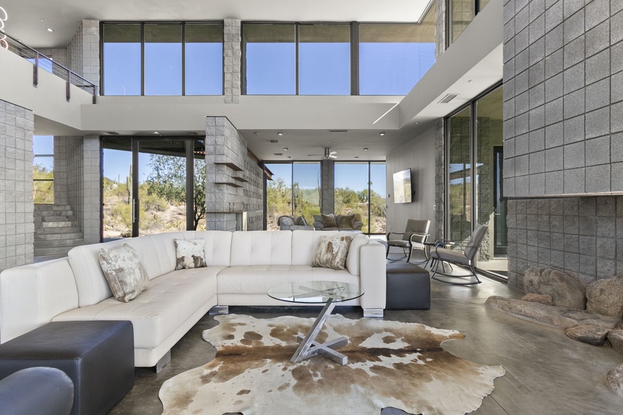 An expansive formal living space bathed in light, featuring chic decor and a statement cowhide rug for a touch of rustic luxury.