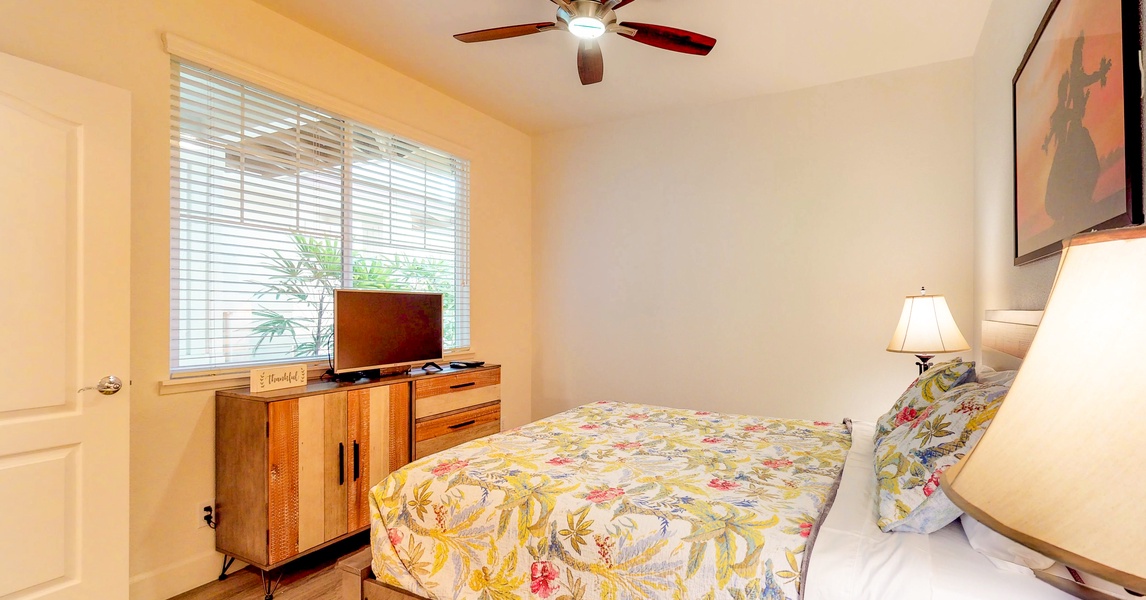The downstairs bedroom has a dresser, TV and ceiling fan.