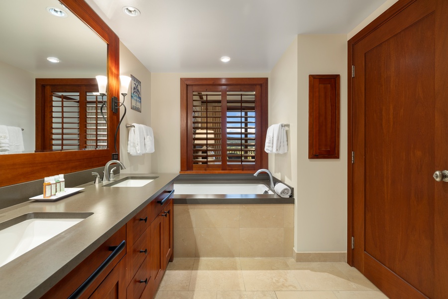 Elegant primary bathroom with large mirror, dual sinks, and soaking tub.