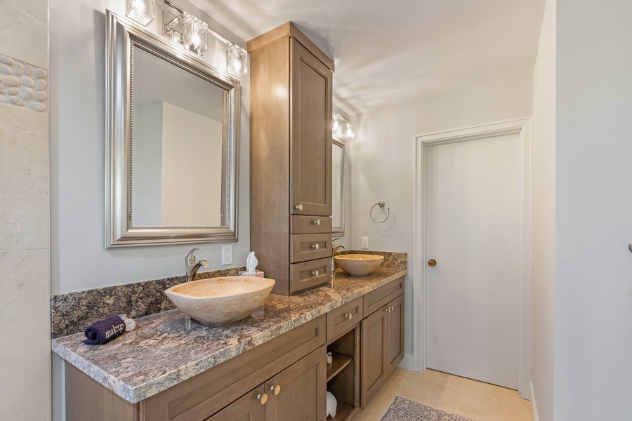 This luxurious ensuite bathroom features dual vessel sinks and elegant wood cabinetr