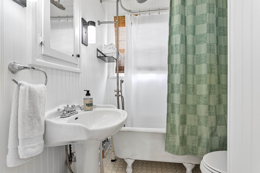 The full bathroom features a vintage-style pedestal sink, tub/shower combo, and fresh linens for every guest.
