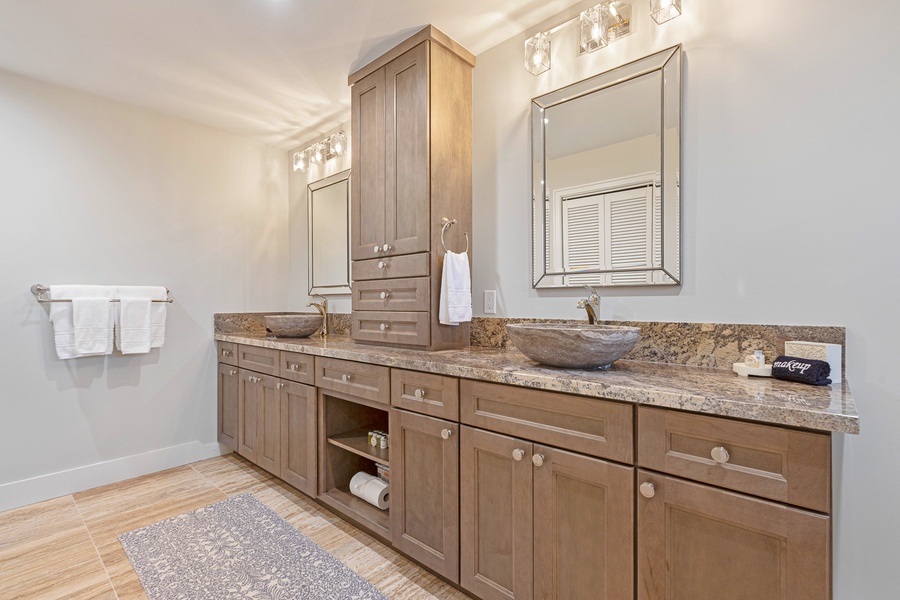 This spacious double vanity bathroom offers ample counter space, rich wood cabinetry, and stylish vessel sinks