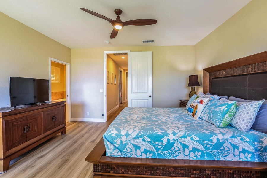 Relax in the primary suite with a Queen bed, ceiling fan, and warm lighting.