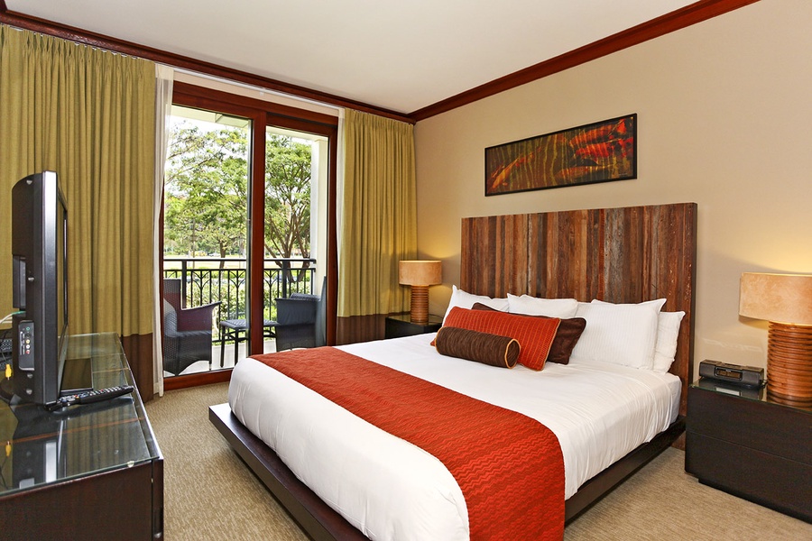 The primary guest bedroom with access to a lanai overlooking a garden and the ocean.