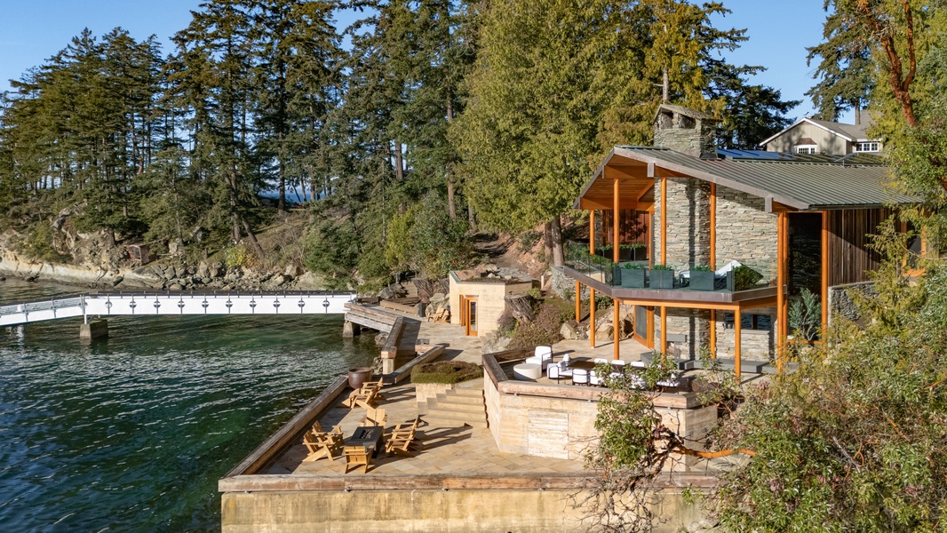 Waterfront retreat with private dock and outdoor seating, surrounded by towering trees and peaceful waters.