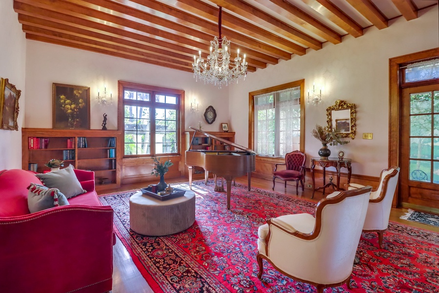 The formal living room, also an antique music room, features high-vaulted acoustic ceilings and luxury appointments, perfect for hosting elegant gatherings or enjoying quiet moments of relaxation.