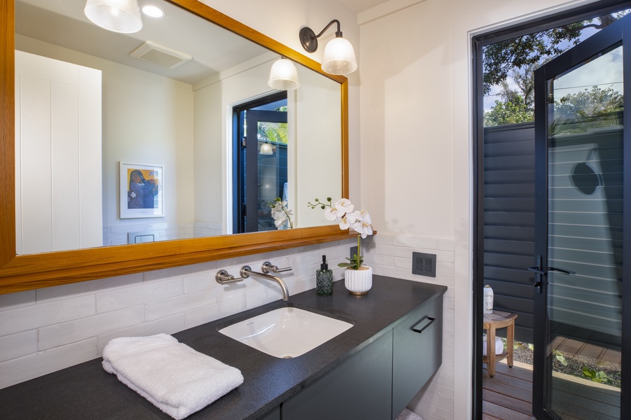 Bright vanity area with a large mirror and an adjacent outdoor view for a unique touch.