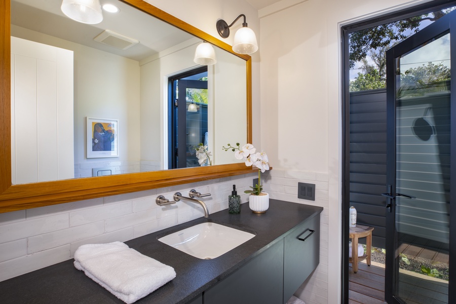 Bright vanity area with a large mirror and an adjacent outdoor view for a unique touch.