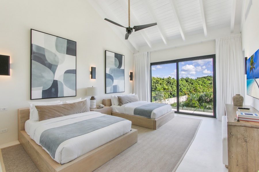 Enjoy the airy bedroom with two beds and a view of the lush landscape.