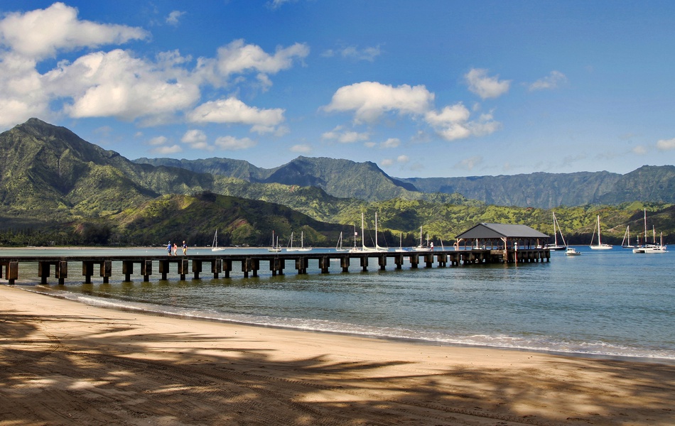 Hanalei Bay with its iconic pier, turquoise waters, and a breathtaking mountain backdrop.