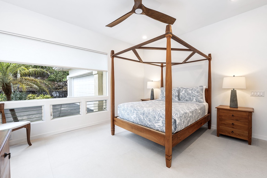 Stylish queen bedroom with canopy bed and garden views, offering private serenity in a bright, airy setting.
