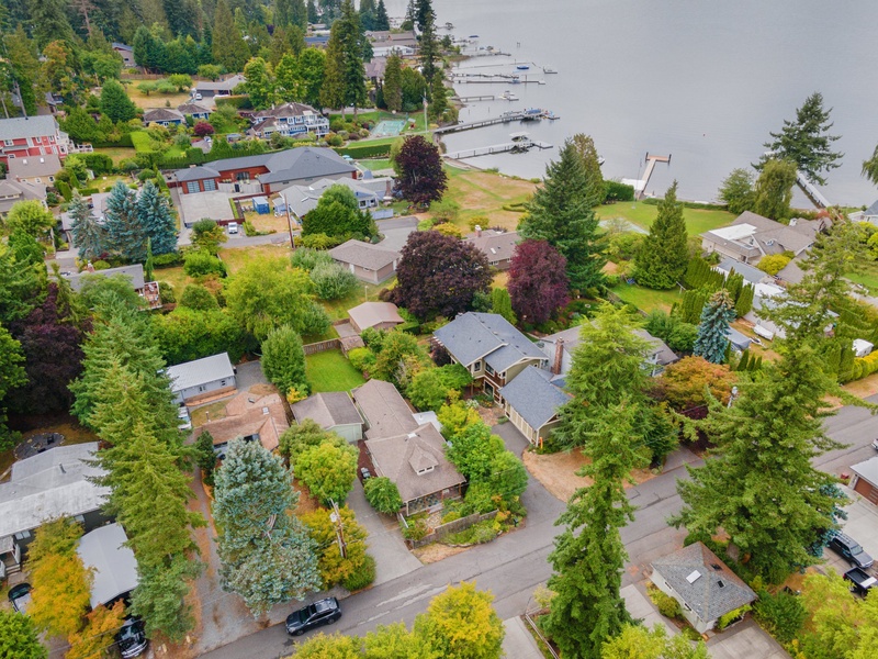 Aerial view of a peaceful lakefront neighborhood with tree-lined streets, waterfront access, and boat docks along the shoreline.
