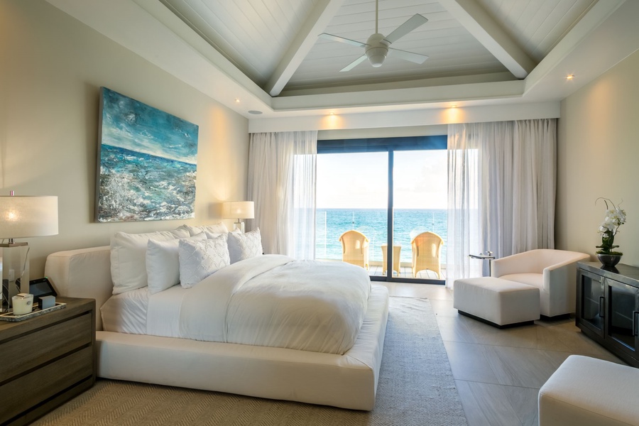 Wake up to stunning ocean views in this luxurious bedroom, featuring a plush bed.