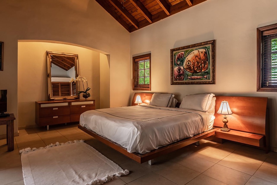 Cozy guest bedroom with charming wooden decor, classic dresser and soft lighting.