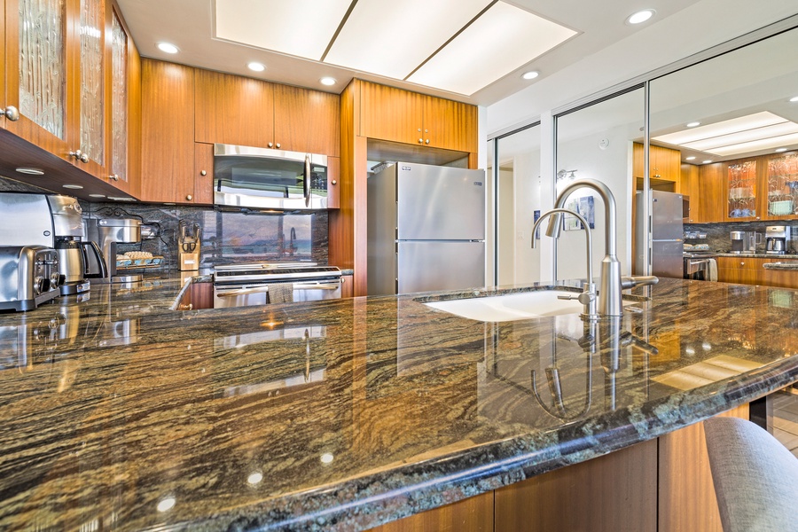 The spacious kitchen countertop with elegant granite offers plenty of room for meal prep or casual dining