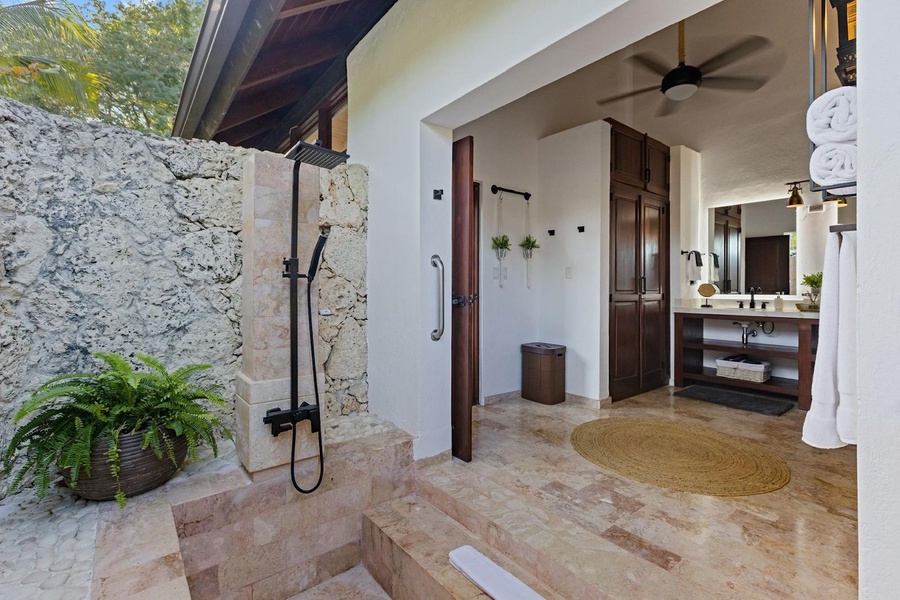 An inviting outdoor shower area with stone walls and a rain shower head.