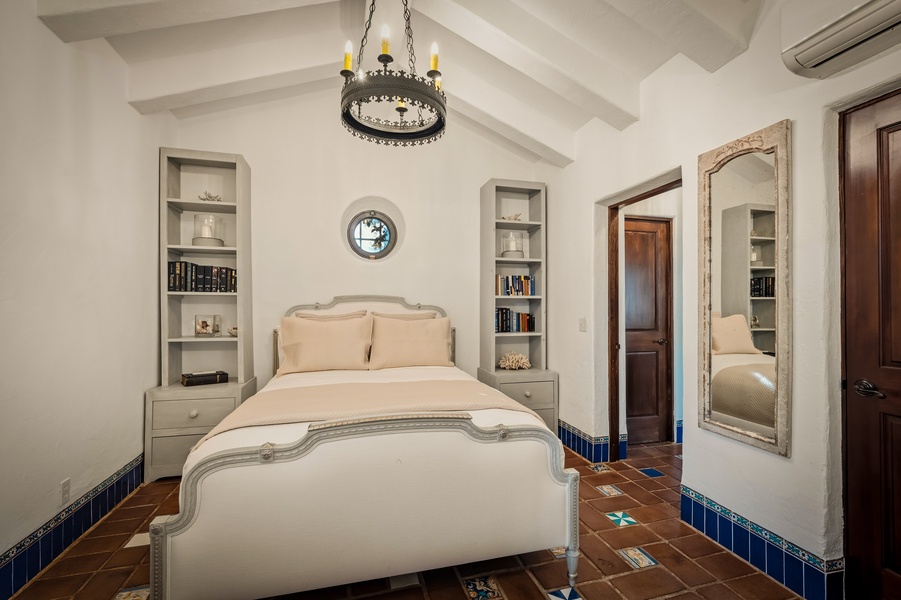 Unwind in your elegant bedroom featuring built-in bookshelves, handcrafted tile floors, and a charming chandelier that creates perfect reading light.