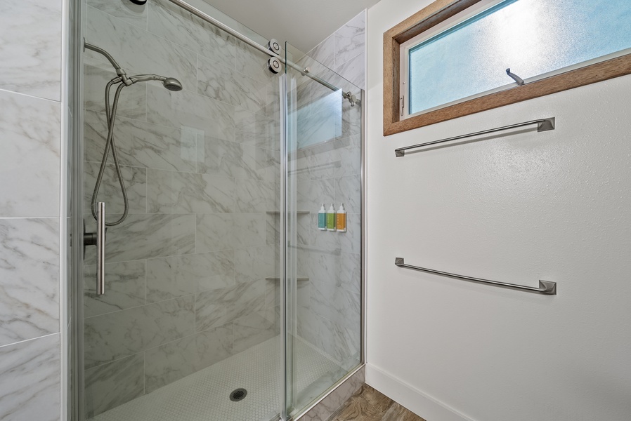 Upgraded en suite bathroom with glass walk-in shower and accessibility-friendly grab bar.