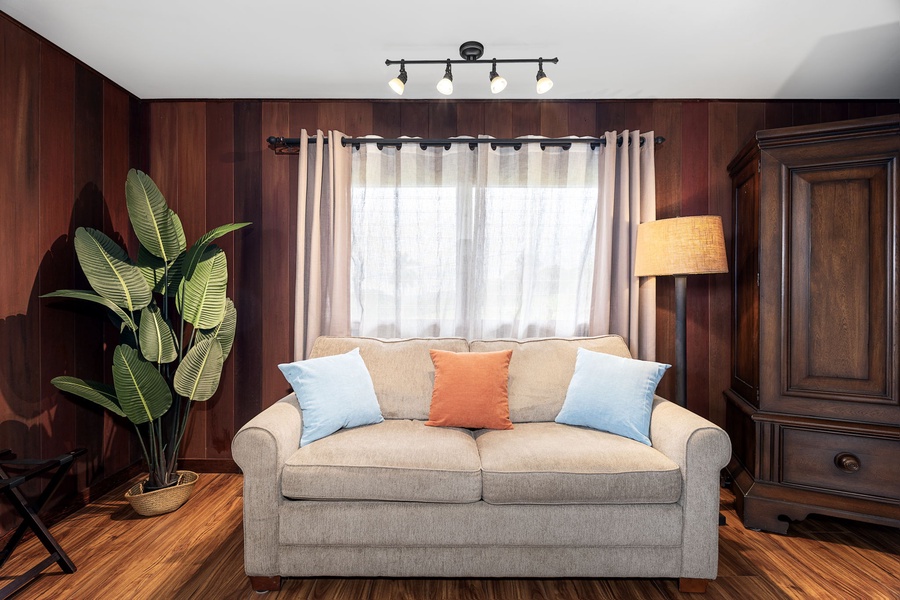Sink into the plush sofa surrounded by warm wood paneling, cheerful throw pillows, and soft natural light filtering through layered curtains—your cozy retreat after a day of exploring.