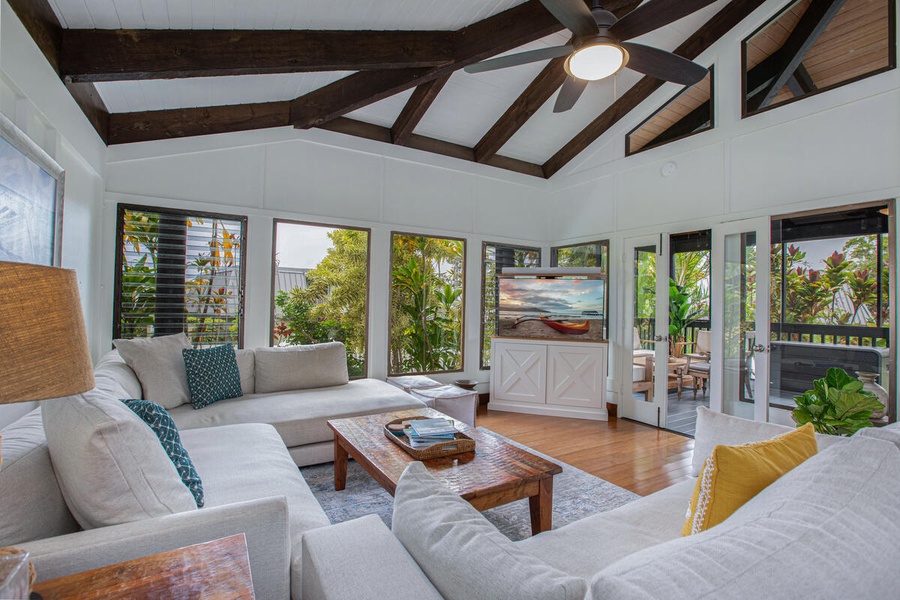 Relax in the light-filled great room featuring vaulted ceilings, tropical decor, and central A/C.