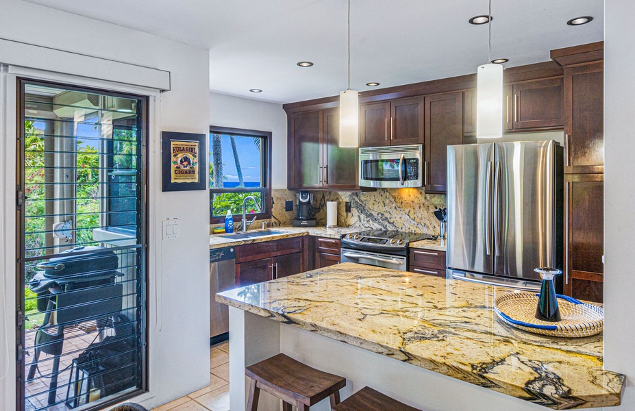 This bright kitchen features a sleek island with granite countertops and a view of the outdoors, making it a comfortable space to prepare meals