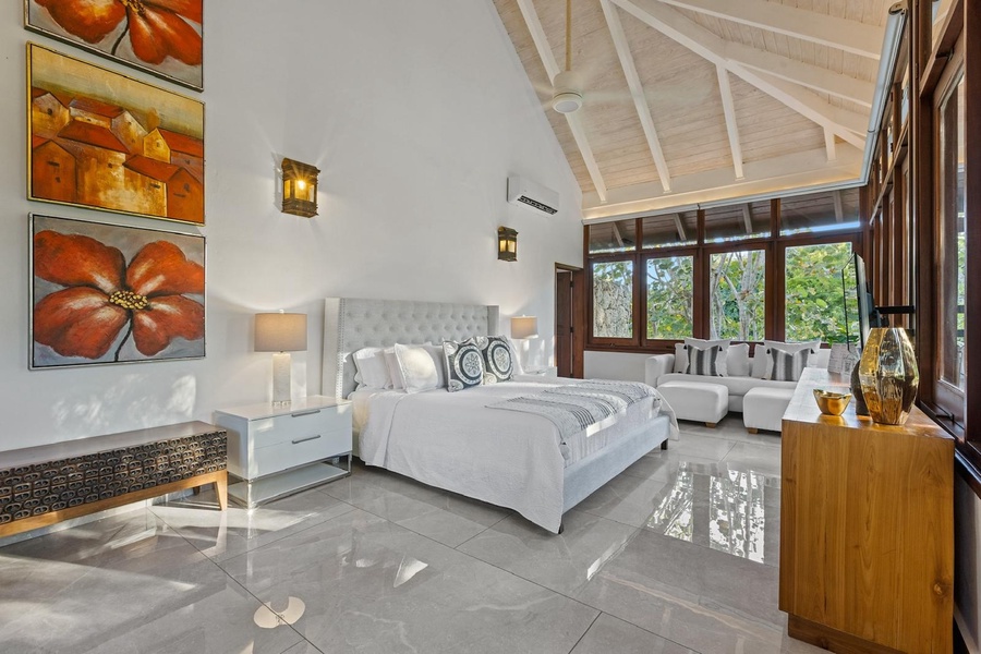 The spacious guest bedroom with plush bed, a comfortable seating area and serene view.