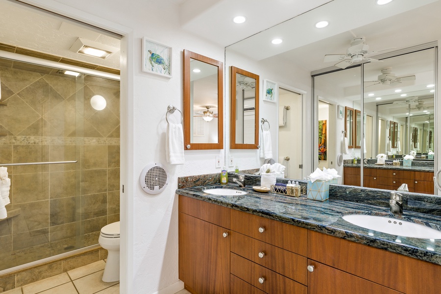 A stylish and well-lit bathroom featuring a spacious vanity with dual sinks and elegant granite countertops