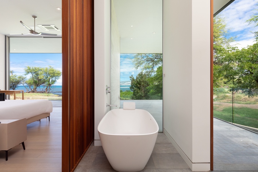 The primary ensuite features expansive views over lush outdoor greenery.