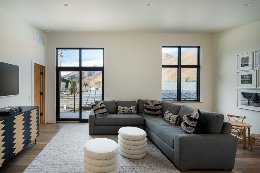 Chic and cozy upper-level living area with a balcony and large windows offering stunning lake views—a serene backdrop for leisure and entertainment.