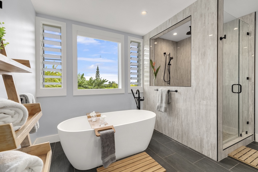 Primary bath with soaking tub, custom shower and views of the greenery outdoors.