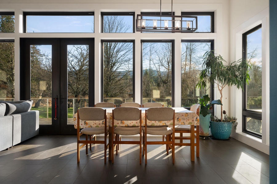 Bright dining table where floor-to-ceiling windows frame peaceful garden views and natural light fills every corner.