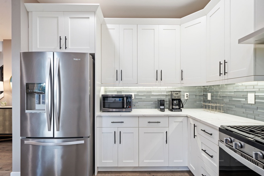 You'll love preparing meals in this spotless white kitchen with stainless steel appliances and elegant tile backsplash.