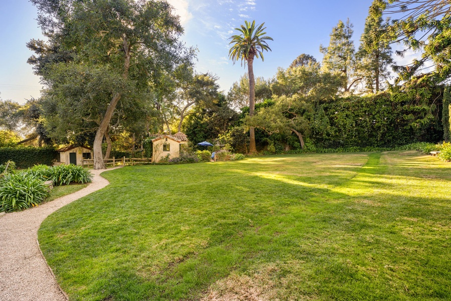Expansive lawn surrounded by mature trees and tropical palms creates a peaceful garden setting perfect for relaxation.