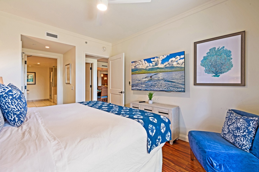 The bedroom offers a relaxing space with a comfortable bed, vibrant artwork, and a flat-screen TV, perfect for unwinding after a day of exploring.