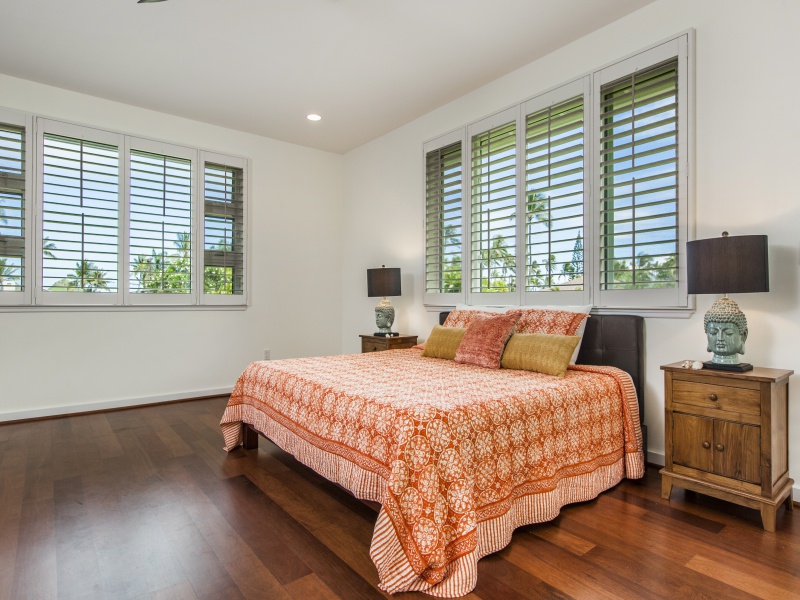 Primary suite with king-size bed and plantation shutters around all the windows.