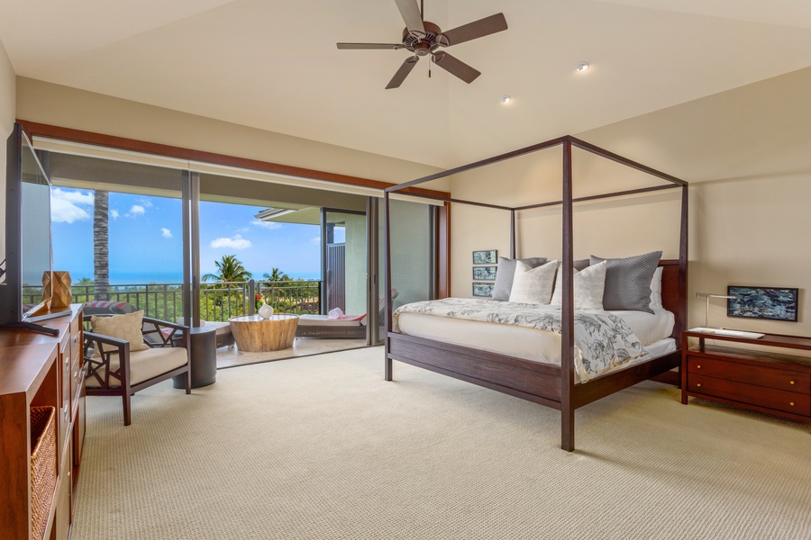 Primary suite with private ocean-view deck, king-size bed, large flat-screen TV, and electric drop-down blinds.
