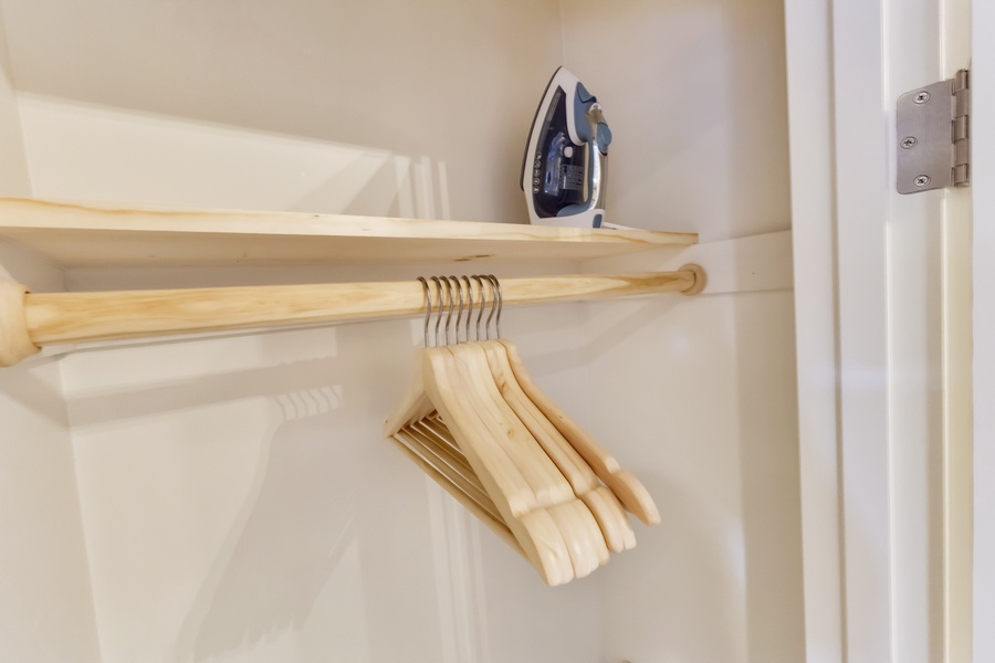 A spacious closet with hangers and an iron ensures you stay organized and neat.