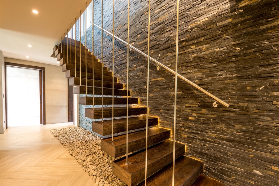 Stylish staircase and a stone accent wall, wooden steps, and modern lighting, adding a touch of sophistication to the space.