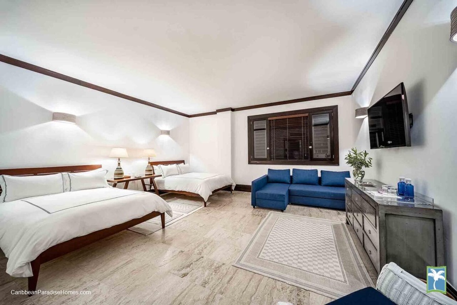 Sleep in this spacious guest bedroom offering two beds, a seating area, and a soothing ambiance.