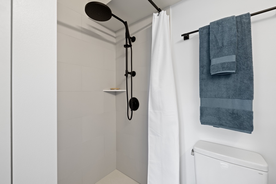 Enjoy a refreshing shower in this sleek and modern bathroom, equipped with a stylish black shower fixture.