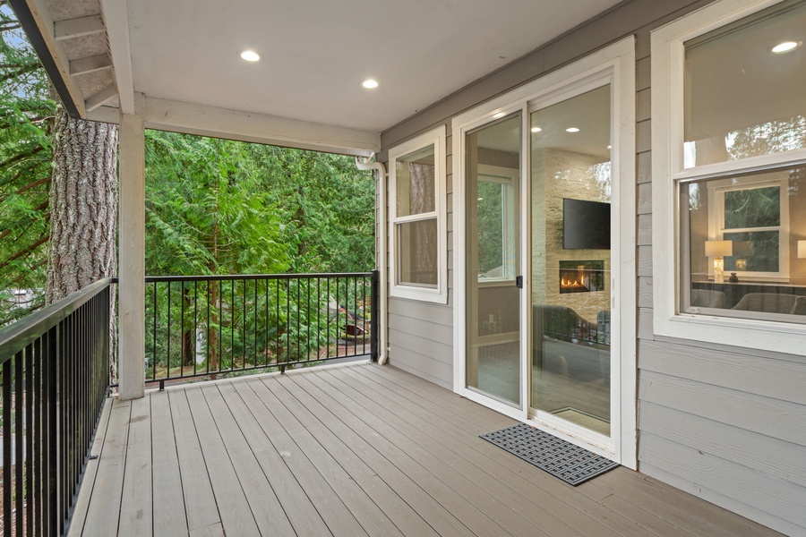 Step onto your lanai where tall trees create a serene forest backdrop and sliding glass doors connect you to the cozy fireplace inside.