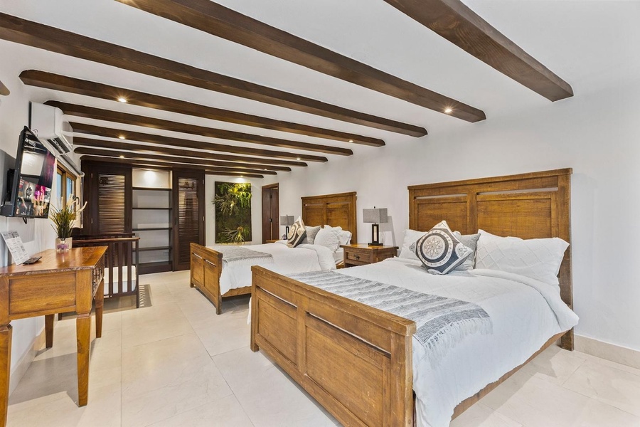 This spacious guest bedroom features two comfortable double beds with wooden headboards and matching furniture.
