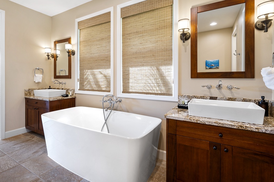 The ensuite primary bath at Kona Blue Vacations Holua Kai features dual vanities and a soaking tub.