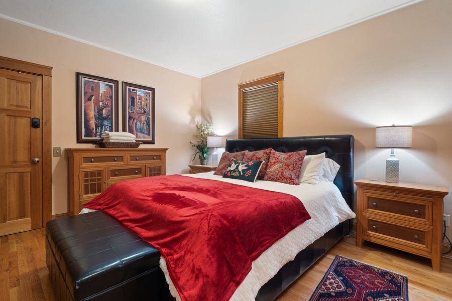 The primary suite features a plush king bed with cozy red accents for winter comfort.