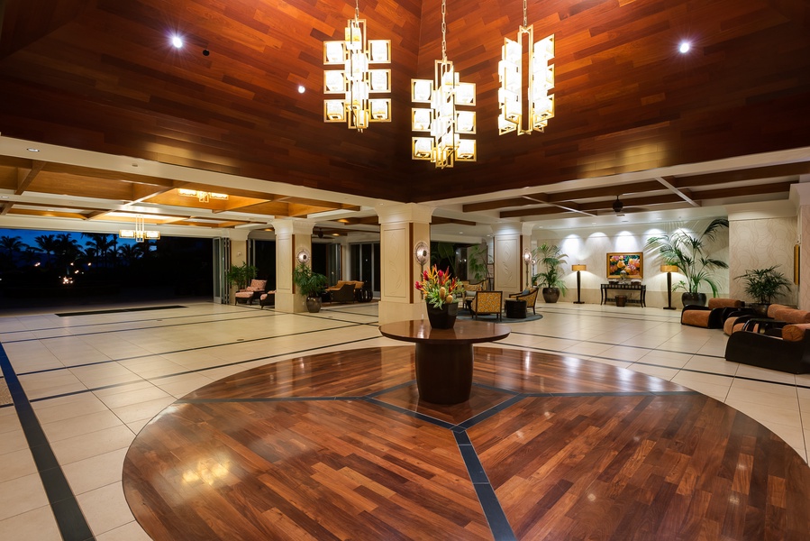 This elegant resort lobby features a rich wooden floor and ceiling, accented by modern hanging light fixtures.